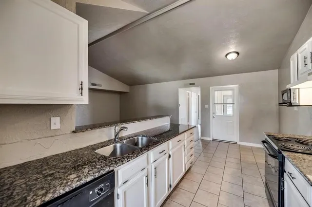 a kitchen with granite countertop a sink stove and cabinets