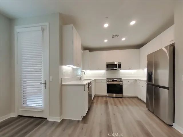 a kitchen with stainless steel appliances a refrigerator sink and wooden floor