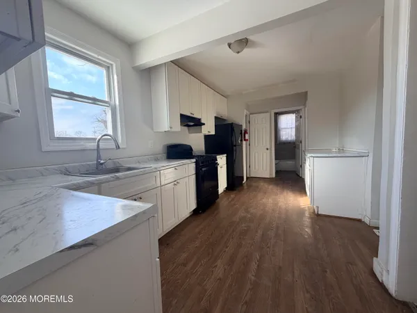 a kitchen with granite countertop a sink cabinets and stainless steel appliances