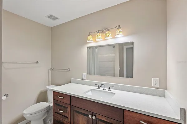 a bathroom with a granite countertop sink vanity mirror and toilet