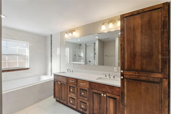 a bathroom with a double vanity sink large mirror and a bathtub