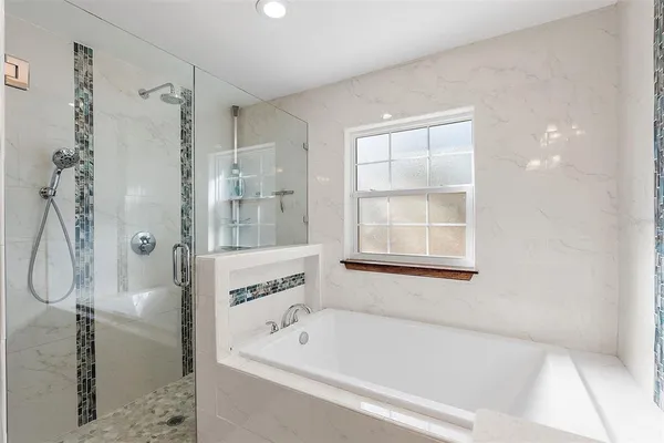 a bathroom with a bathtub a shower and a window