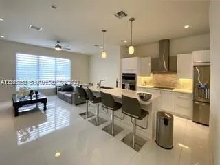a kitchen with stainless steel appliances granite countertop a refrigerator a sink dishwasher a dining table and chairs with wooden floor
