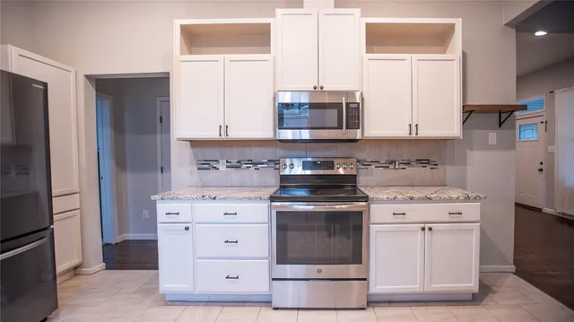 a kitchen with stainless steel appliances white cabinets and a stove a refrigerator with wooden floor