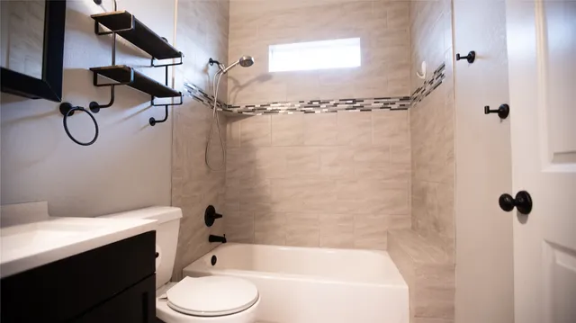 a bathroom with a granite countertop bathtub shower sink vanity and toilet