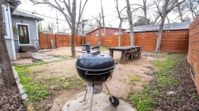 a view of a backyard with table and chairs potted plants and wooden fence