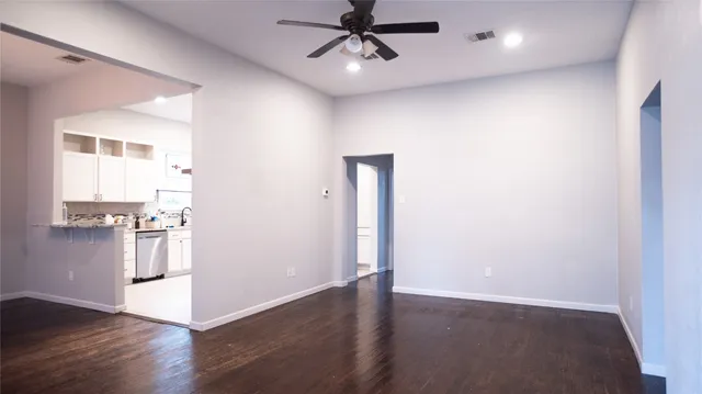 an empty room with wooden floor and a ceiling fan