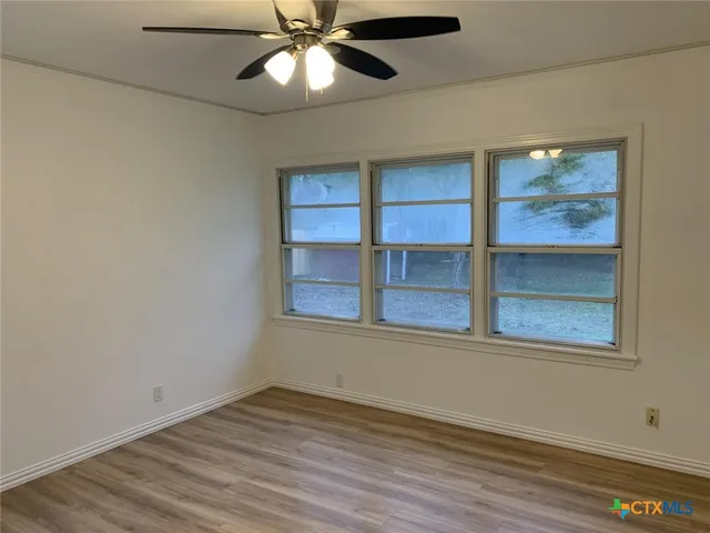 an empty room with wooden floor closet and windows
