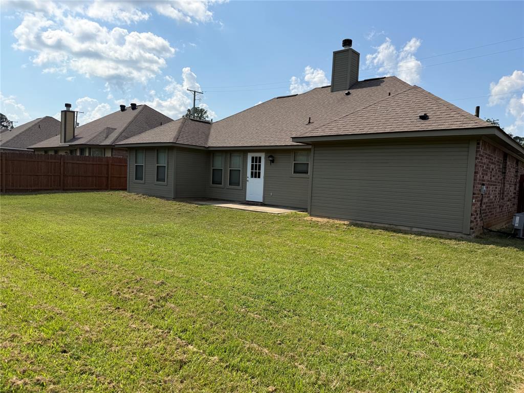 520 Big Red Circle Haughton, LA 71037 - Photo 23 of 25 Spacious backyard featuring a manicured lawn, a brown privacy fence, a rear patio, and a white exterior door