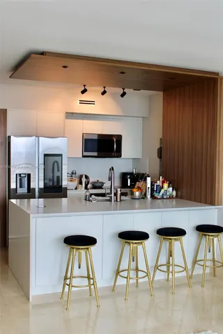 a kitchen with refrigerator and chairs