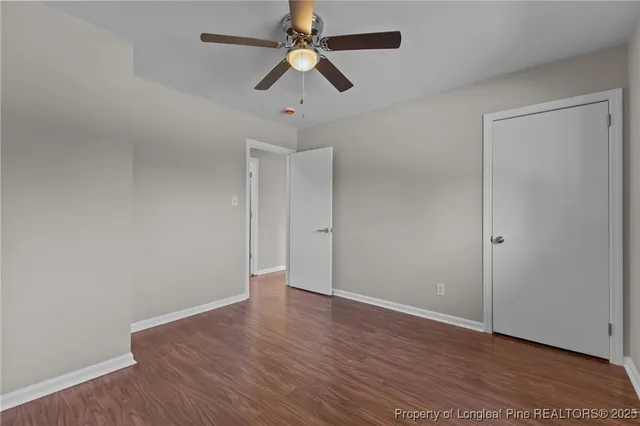 an empty room with wooden floor ceiling fan and window