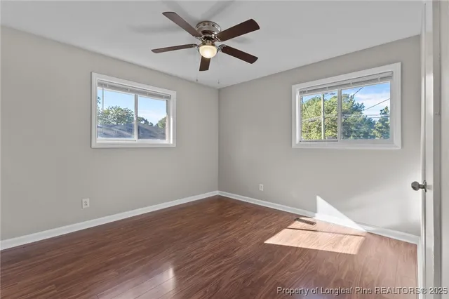 a view of empty room with wooden floor and fan