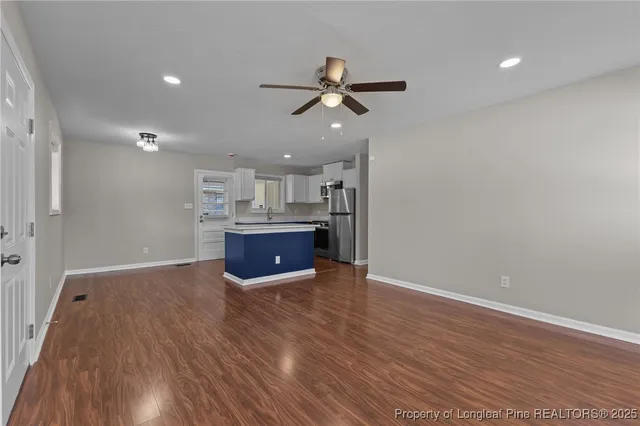 a view of kitchen and empty room with wooden floor