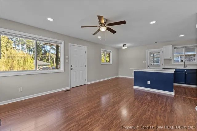 a workspace with wooden floor a ceiling fan and windows