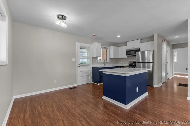 a room with stainless steel appliances kitchen island granite countertop a refrigerator and a sink