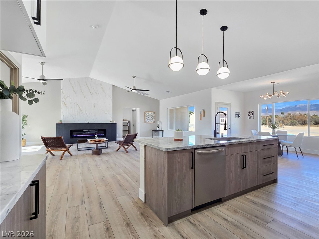 1120 West Gamebird Road Pahrump, NV 89048 - Photo 35 of 36 Kitchen with open floor plan, vaulted ceiling, light stone countertops, pendant lighting, and light wood finished floors