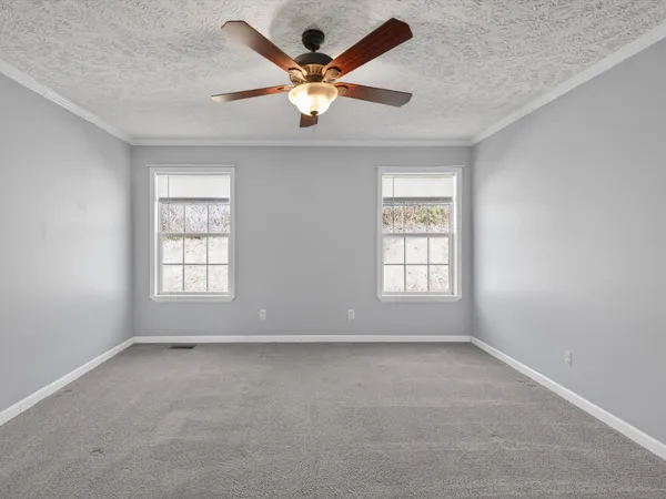 an empty room with window and ceiling fan