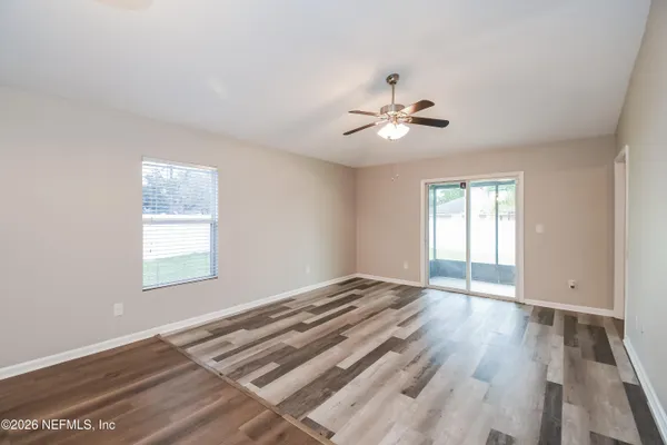 a view of an empty room with a window and wooden floor