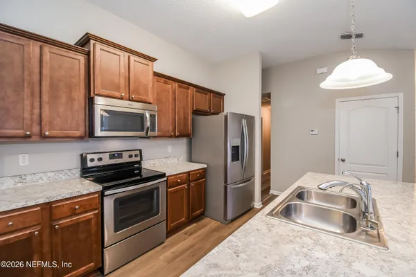 a kitchen with granite countertop a refrigerator stove and microwave