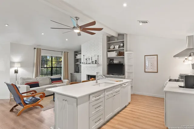 a view of kitchen island a sink wooden floor and a window