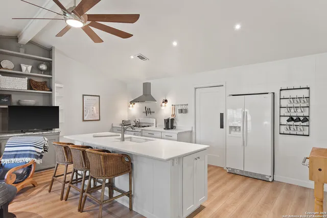 a kitchen with stainless steel appliances kitchen island granite countertop a table chairs and a refrigerator