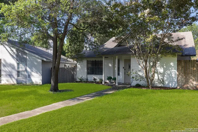 a front view of a house with a yard and tree