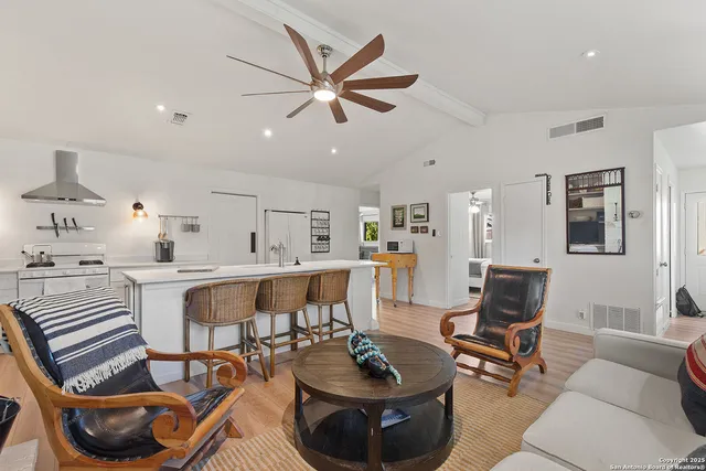 a living room with furniture and a dining table with wooden floor