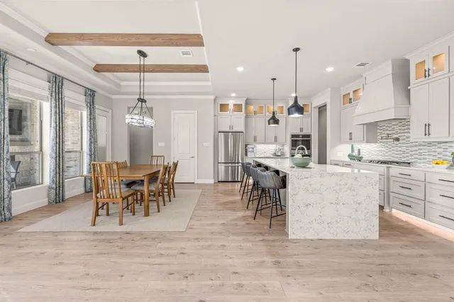 a dining hall with stainless steel appliances kitchen island granite countertop a dining table chairs and view living room