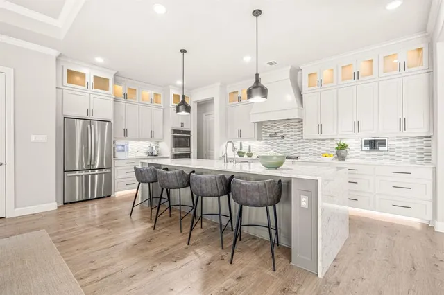 a kitchen with stainless steel appliances kitchen island granite countertop a table chairs sink and cabinets