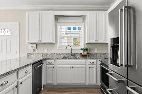 a kitchen with granite countertop white cabinets white stainless steel appliances and a sink