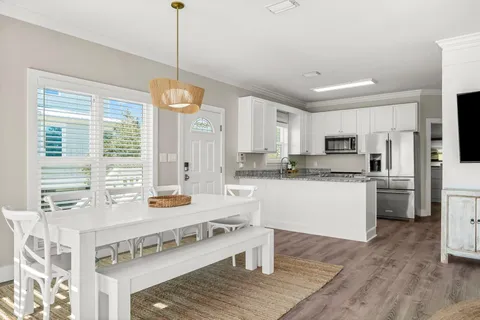 a kitchen with stainless steel appliances granite countertop a stove a sink dishwasher a refrigerator white cabinets and wooden floor