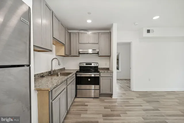 a kitchen with stainless steel appliances granite countertop a stove sink and cabinets