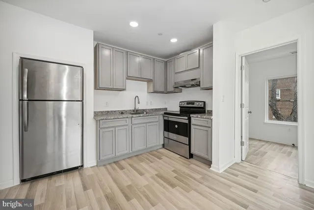 a kitchen with a refrigerator a stove top oven and wooden floor
