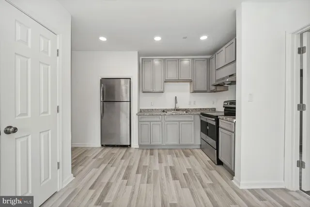 a kitchen with a refrigerator a stove top oven and wooden floor