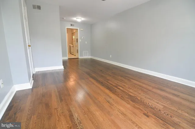 a view of an empty room with wooden floor and a window
