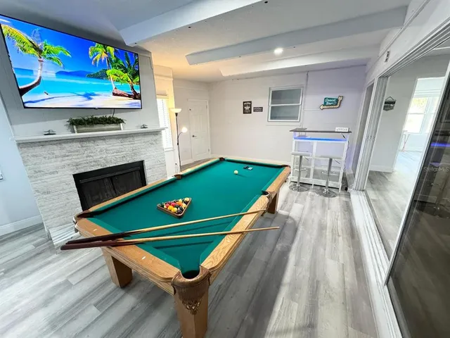 a room with pool table windows and wooden floor