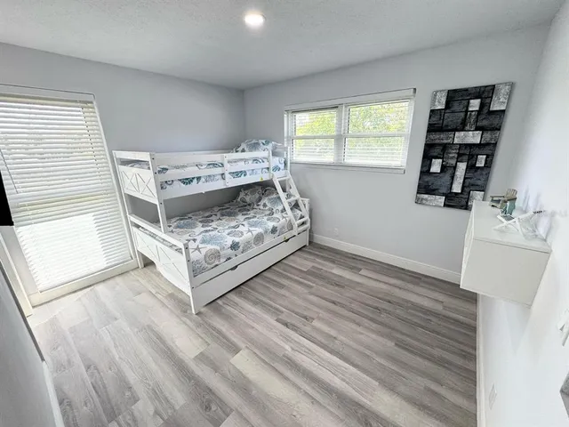a view of a bedroom with wooden floor and window