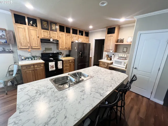 a kitchen with stainless steel appliances kitchen island granite countertop a table chairs and a refrigerator
