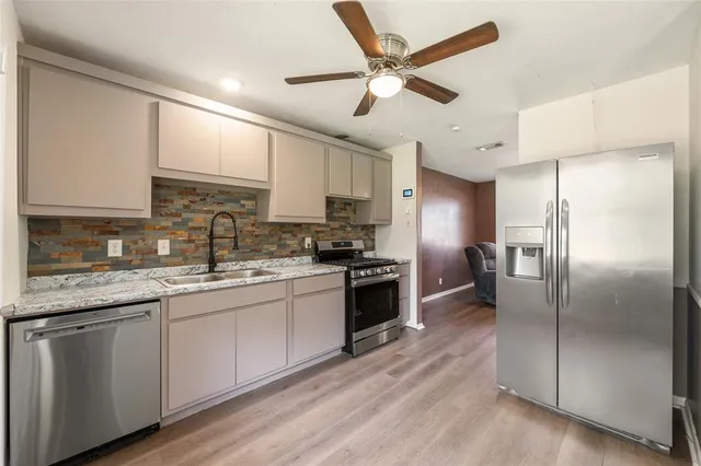 a kitchen with a refrigerator a sink stainless steel appliances and cabinets