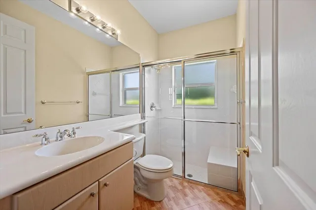 a bathroom with a granite countertop sink toilet a mirror a vanity and shower