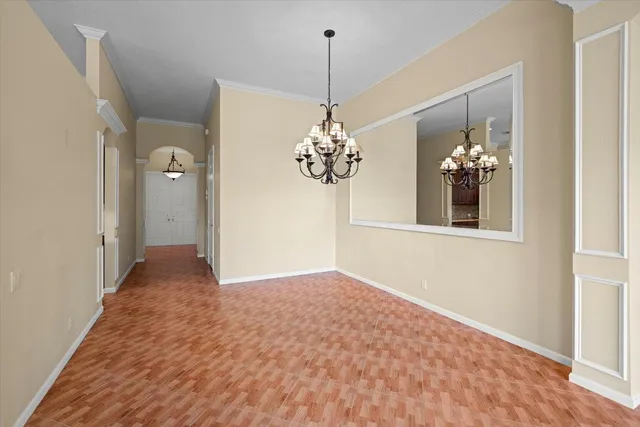 a view of an empty room with chandelier fan and wooden floor