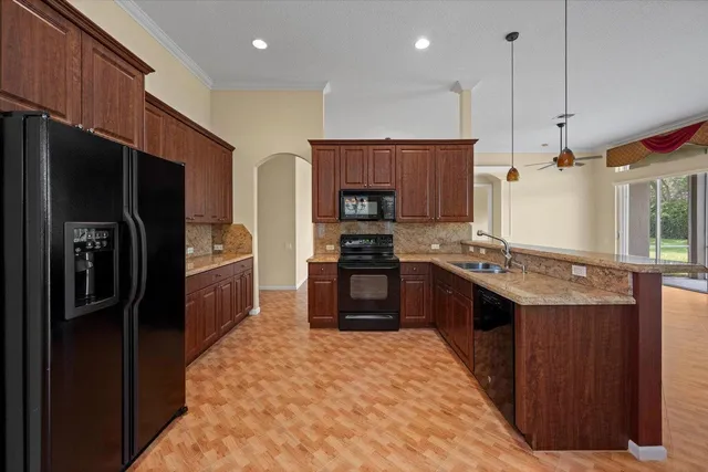 a kitchen with stainless steel appliances granite countertop a refrigerator a stove a sink and a oven