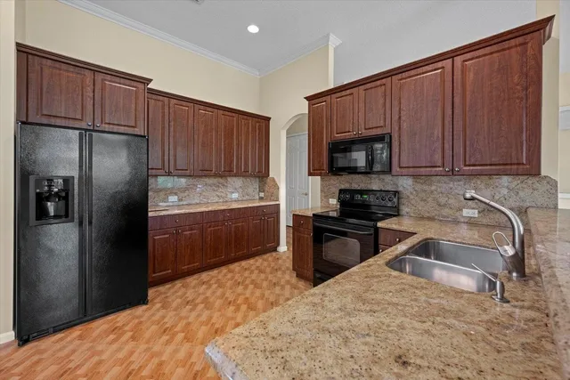 a kitchen with granite countertop wooden cabinets a refrigerator and a sink