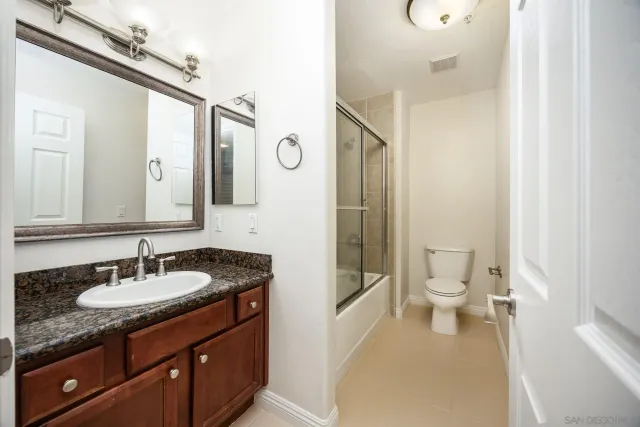 a bathroom with a granite countertop sink toilet and shower