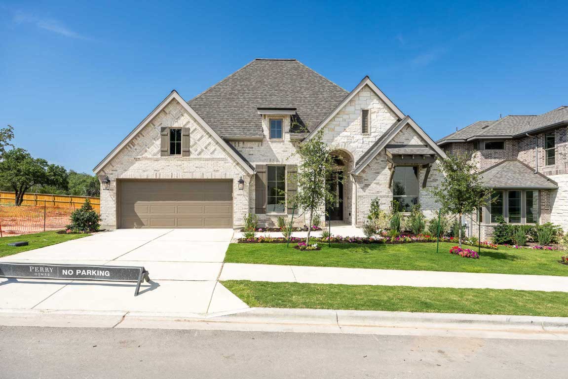 French country home featuring concrete driveway, stone siding, brick siding, and roof with shingles