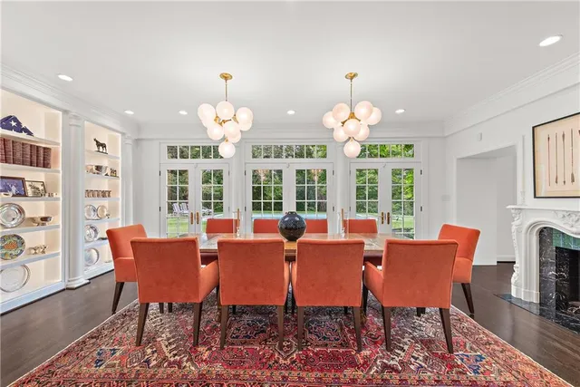 a dining room with wooden floor a chandelier a flat screen tv and a chandelier