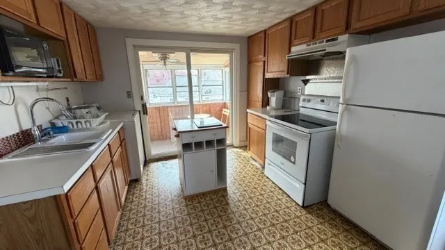 a kitchen with a sink a stove top oven a refrigerator and cabinets