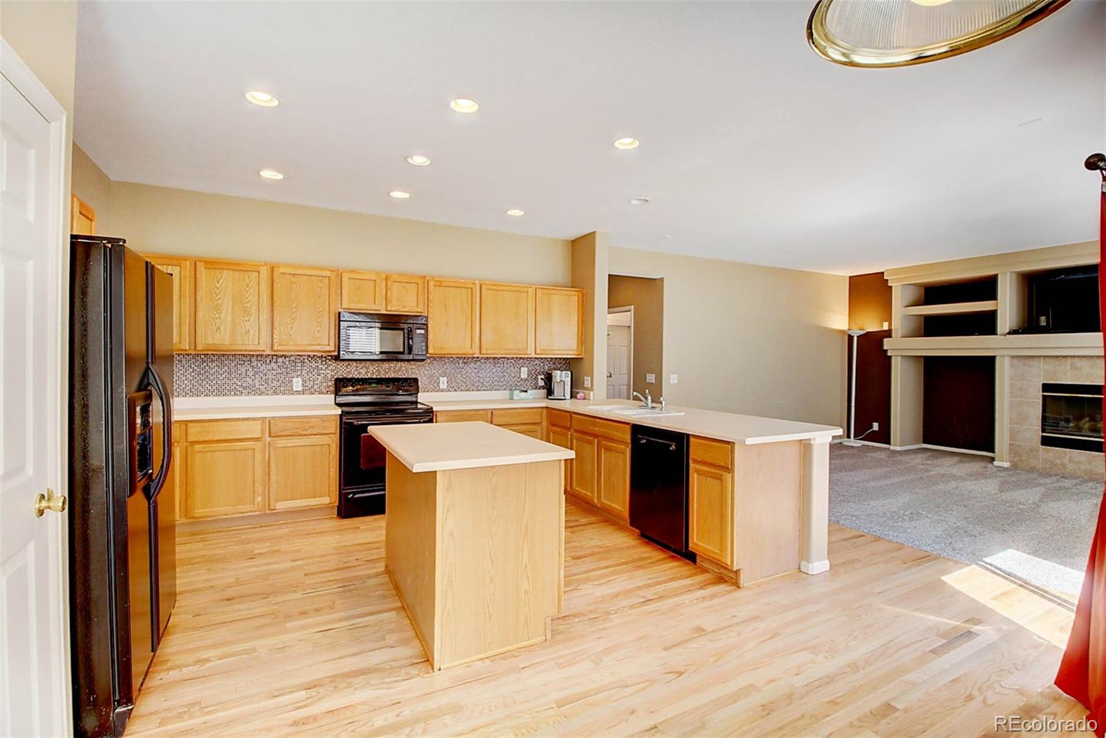 5794 South Rome Street Aurora, CO 80015 - Photo 9 of 37 a large kitchen with stainless steel appliances granite countertop a stove a sink dishwasher and a refrigerator with wooden floor