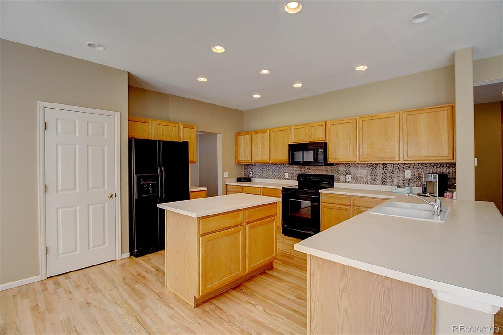 5794 South Rome Street Aurora, CO 80015 - Photo 10 of 37 a kitchen with stainless steel appliances granite countertop a stove top oven a refrigerator a sink and dishwasher with wooden floor
