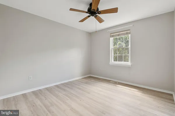an empty room with a window and a fan